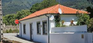 a small white building with an orange roof next to a stop sign at Casa da Venda in Ponte de Lima