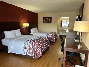 a hotel room with two beds and a desk at Red Roof Inn Fredericksburg South in Fredericksburg