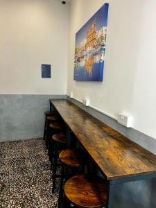 a long counter with chairs and a painting on the wall at Bookarest Hostel Malta in St Julian's