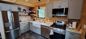 a kitchen with white cabinets and a stainless steel refrigerator at Lochaber Homesteader Lodge in Antigonish