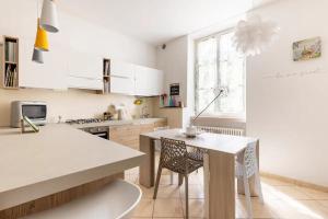 a kitchen with white cabinets and a table with chairs at Piccola Venezia - Borgo Valsugana in Borgo