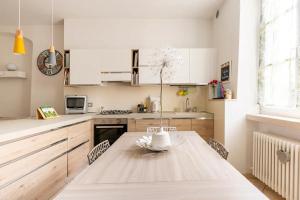 una cocina con mesa de madera y una cocina con armarios blancos. en Piccola Venezia - Borgo Valsugana, en Borgo