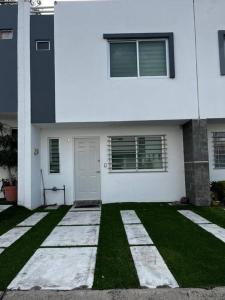 ein weißes Haus mit einem Rasenplatz davor in der Unterkunft Casa Cotito in Guadalajara