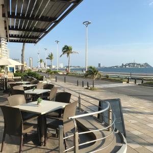 Olas Altas Inn Hotel & Spa في مازاتلان: مطعم به طاولات وكراسي والشاطئ