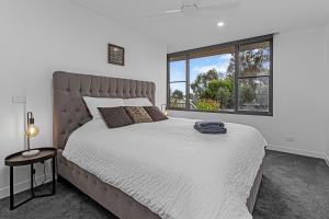 een slaapkamer met een groot bed en een groot raam bij Luxurious Haven House by the Beachside Ocean Grove in Ocean Grove