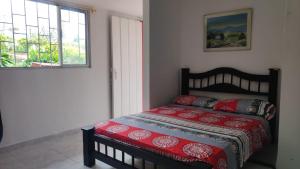 1 dormitorio con 1 cama con edredón rojo y 2 ventanas en Finca Hotel Villa Luna, en Armenia