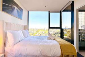 a bedroom with a white bed with a large window at Luxury Condo w/ Ocean View, Pool, Gym near Crown in Melbourne