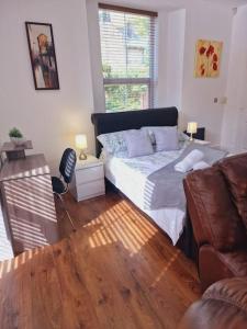 a bedroom with a bed and a couch and a wooden floor at The Cosy Corner studio in Sheffield