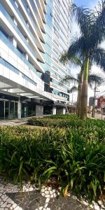 un edificio con una palmera delante de él en Excelente Studio Completo Centro Curitiba - Ar Condicionado - 7th Avenue en Curitiba