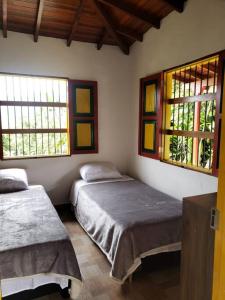 1 dormitorio con 2 camas y 2 ventanas en Casa de Campo el mirador, en Jericó