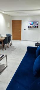 Les Belles Appartements Family Only في طنجة: غرفة معيشة مع أريكة زرقاء وطاولة