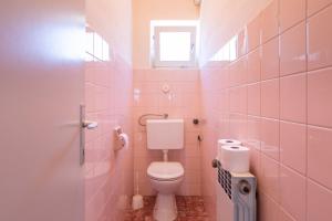 a pink bathroom with a toilet and a window at Apartments in Crikvenica 41682 in Crikvenica