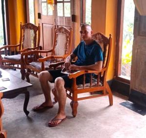 un homme assis dans une chaise dans une pièce dans l'établissement Coca Cola Hostel Malabe, à Malabe