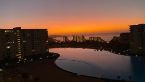 una puesta de sol sobre una piscina en una ciudad con edificios en Departamento laguna bahía sol, en Algarrobo
