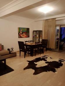 Bel appartement à skhirat plage et à 20 mn de Rabat في الصخيرات‎: غرفة معيشة مع طاولة وكراسي وسجادة