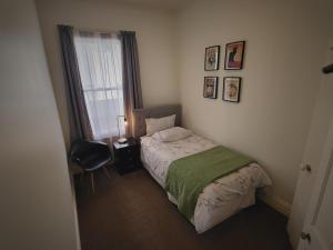 Un dormitorio con una cama y una silla y una ventana. en Central Victoria Oasis, en Hamilton