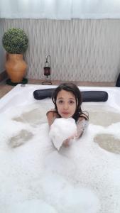 una niña pequeña en una bañera sosteniendo un corazón en LOFT do Sonho!, en Palhoça