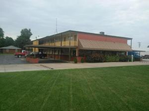 a large building with a green lawn in front of it at Big Bend Traveler's Inn in Great Bend