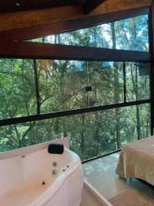a bathroom with a tub in front of a large window at Refúgio na Serrinha do Alambari - Penedo -RJ in Resende