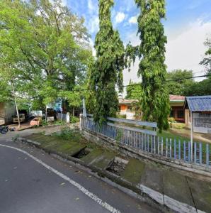 uma rua com uma cerca e árvores e uma casa em Guest House Dorm Floressa em Maumere