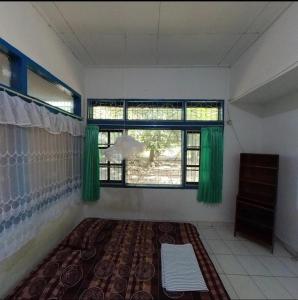 een kamer met groene gordijnen en een groot raam bij Guest House Dorm Floressa in Maumere