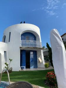 a white house with a blue door and a balcony at CASA DE REVISTA em Cabo Frio in Cabo Frio