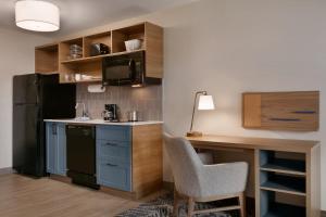 una pequeña cocina con escritorio y nevera negra en Candlewood Suites Kansas City Northeast, an IHG Hotel en Kansas City