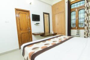 a bedroom with a large bed and a tv at OYO Hotel Indiana Near Gomti Riverfront Park in Vibhuti Khand