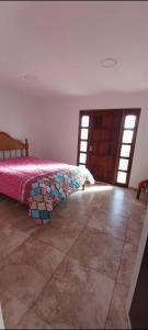 1 dormitorio con 1 cama con colcha rosa en FAROLE en Rodeo de la Cruz