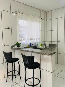 una cocina con 2 sillas negras y una barra en apartamento inteiro en Cuiabá