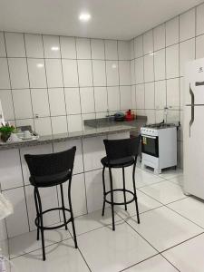 - deux chaises dans une cuisine avec un comptoir et un réfrigérateur dans l'établissement apartamento inteiro, à Cuiabá