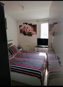 a bedroom with a bed with a striped comforter at Joli Duplex entièrement meublé in Chanteloup-les-Vignes