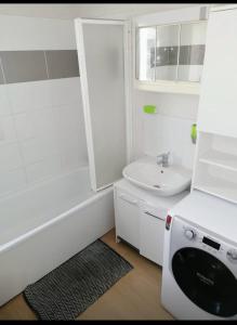 a white bathroom with a tub and a sink at Joli Duplex entièrement meublé in Chanteloup-les-Vignes