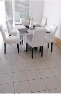 a dining room with a table and white chairs at Joli Duplex entièrement meublé in Chanteloup-les-Vignes