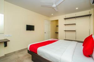 a bedroom with a red and white bed and a tv at Super OYO Flagship Olivia Comforts Near Nexus Mall Koramangala in Bangalore