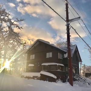 Una casa en la nieve con el sol detrás. en Japow House en Myoko