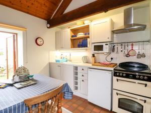 a kitchen with a table and a stove top oven at Manifold Cottage in Grindon +13 photos
