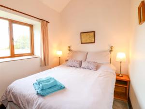 a bedroom with a white bed with two lamps at Manifold Cottage in Grindon