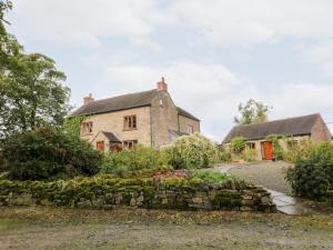 an old stone wall in front of a house at Manifold Cottage in Grindon