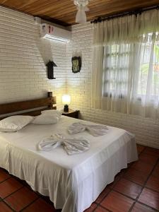 a bedroom with a bed with white sheets and a window at Pousada House Sol & Praia in Torres