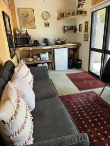 a living room with a couch and a kitchen at Kākā Ridge Retreat Bush Hideaway in Tawharanui