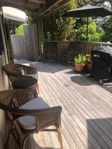 eine Holzterrasse mit Stühlen und einem Sonnenschirm in der Unterkunft Kākā Ridge Retreat Bush Hideaway in Tawharanui