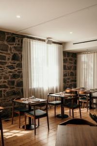 a dining room with tables and chairs and a stone wall at The Oak & Anchor Hotel in Port Fairy