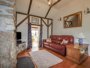 a living room with a leather couch and a table at Jolls Ground Barn in Altarnun