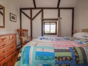 a bedroom with a bed and a chair and a window at Jolls Ground Barn in Altarnun