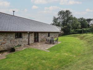 a stone cottage with a table and chairs in the yard at Jolls Ground Barn in Altarnun