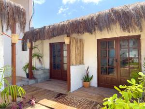a house with wooden doors and a thatched roof at VILA LITORANEA a in São Luís