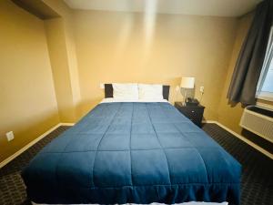 a hotel room with a bed with a blue blanket at Voyageur Motel in Rocky Mountain House