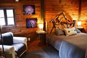 a bedroom with a bed and a chair in a log cabin at El Rincon Eco Hotel in Los Ángeles
