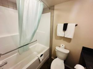 a bathroom with a tub and a toilet and a shower at Voyageur Motel in Rocky Mountain House